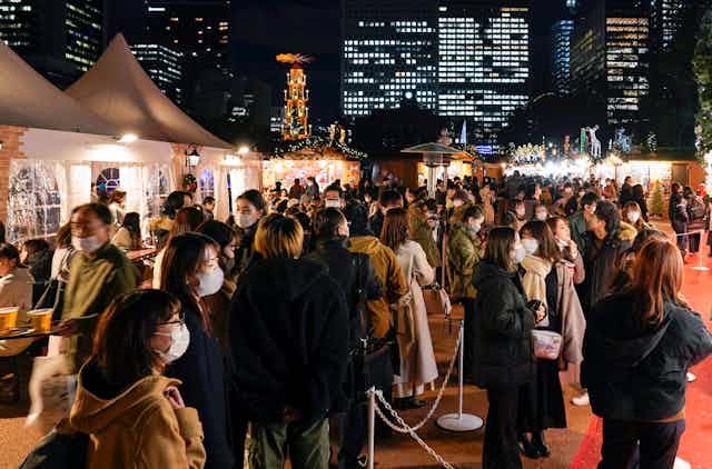 A crowd of people wearing masks attend a Christmas market in Tokyo.
