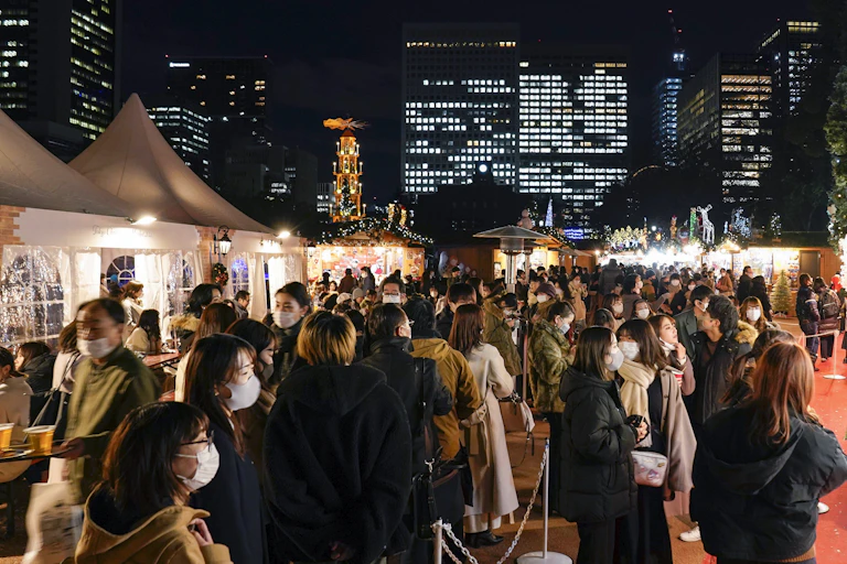 A crowd of people wearing masks attend a Christmas market in Tokyo.