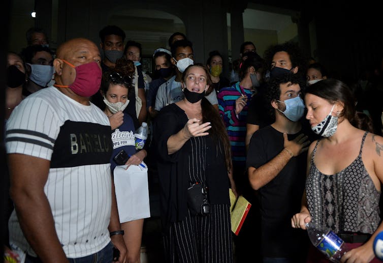 Habla una mujer de negro con una mascarilla, rodeada de una multitud