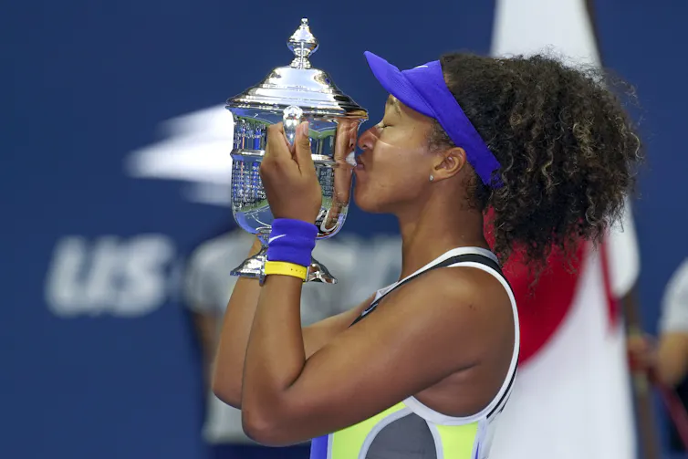 Naomi Osaka kisses the U.S. Open trophy.