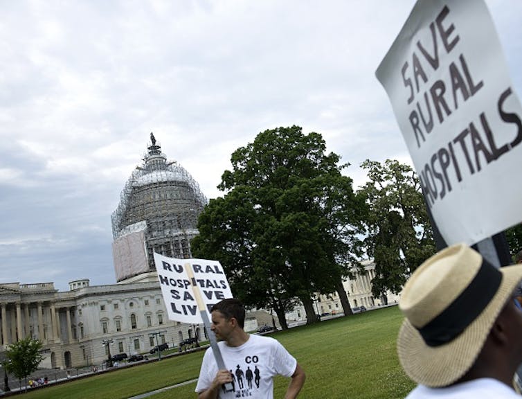 Activists hold signs that say: Save rural hospitals.