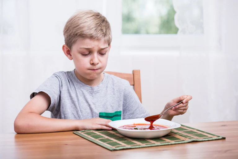 Boy looks at his bowl of soup in disgust.