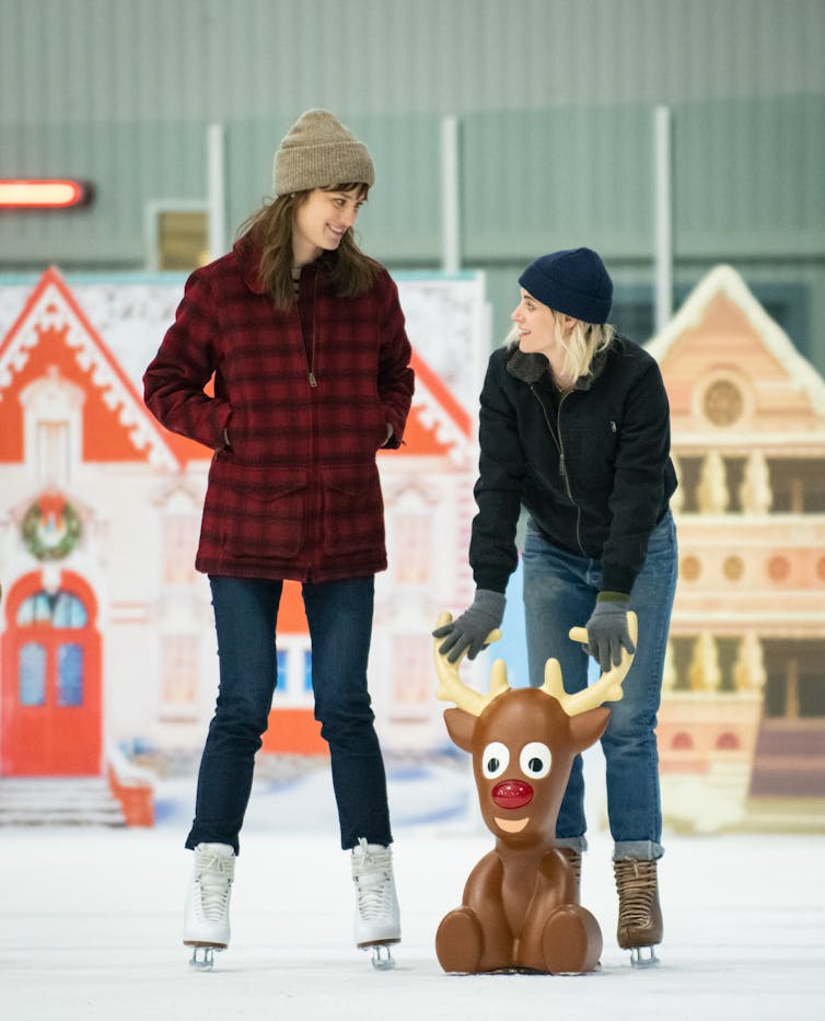 Two women ice skating with brown reindeer figurine