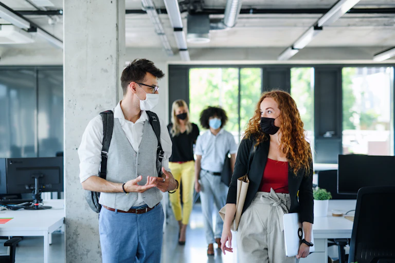 People wearing masks walk through an office space