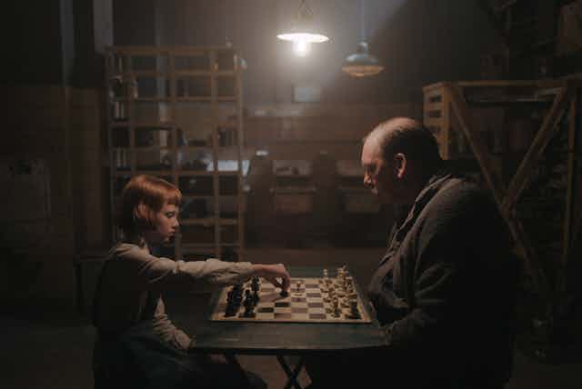 Old man and young girl playing chess