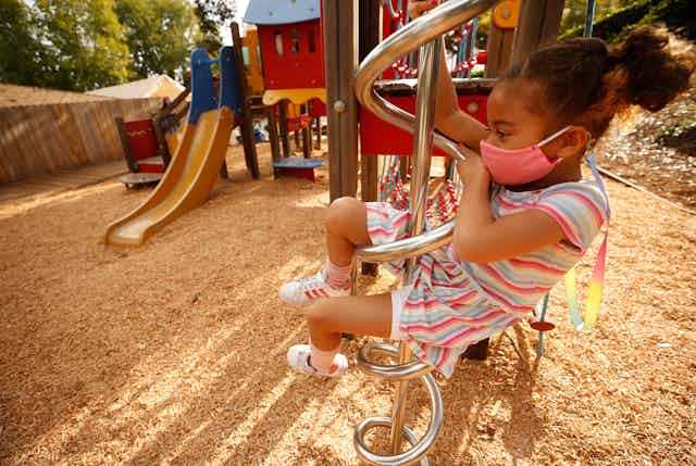 Young girl climbs playground equipment