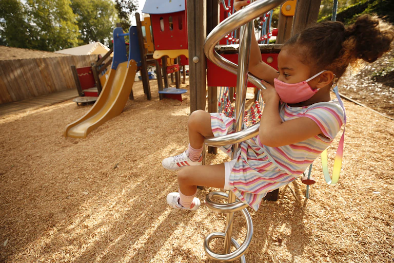 Young girl climbs playground equipment