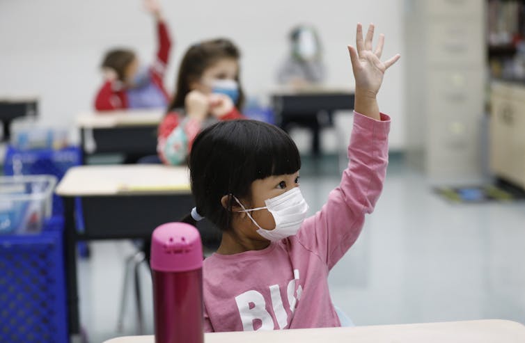 Young girl raises hand in classroom