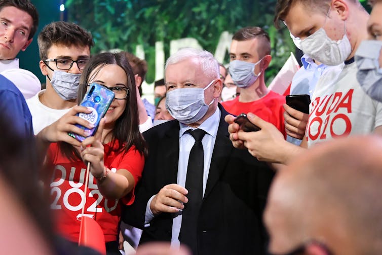 Jaroslaw Kaczynski posing for selfies with fans.