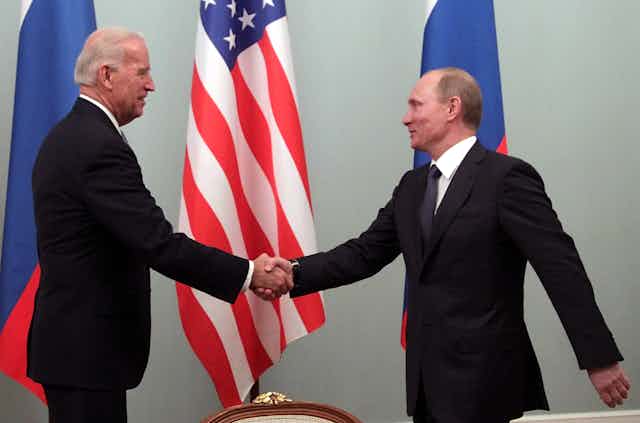 Joe Biden shakes hands with Vladimir Putin.