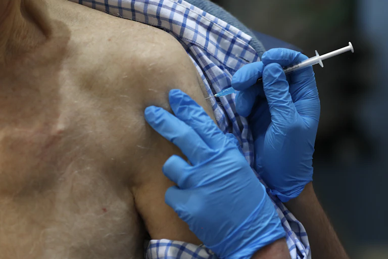 A healthcare worker gives a shot of the Pfizer coronavirus vaccine to an elderly woman.