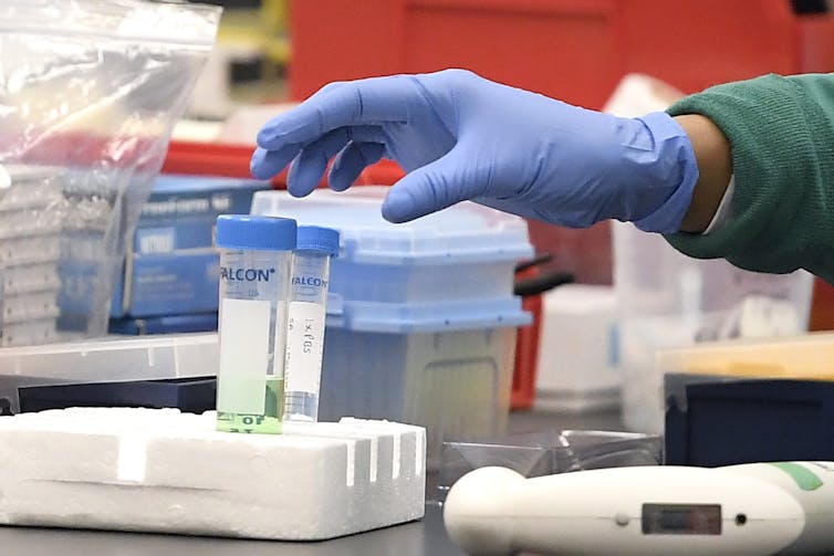 A researcher working with vials of COVID-19 in a lab.