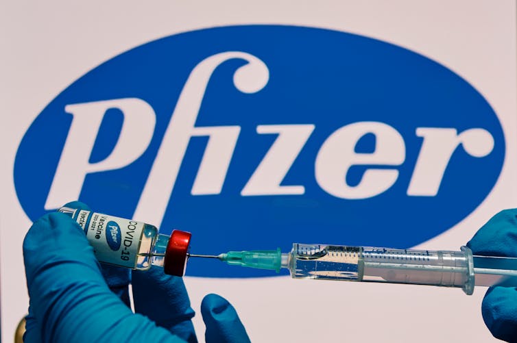 A researcher loading a syringe with the Pfizer COVID-19 vaccine