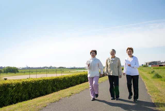 Three elderly women walking outdoors together.