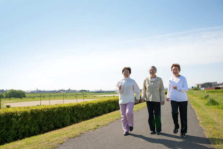 Three elderly women walking outdoors together.