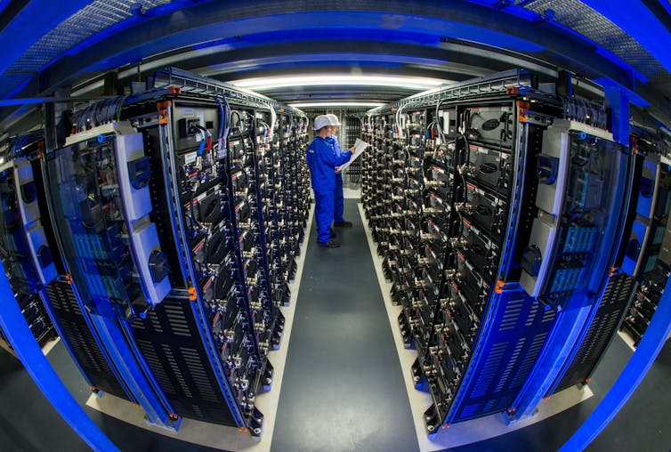 Two engineers inspect shelves of equipment.
