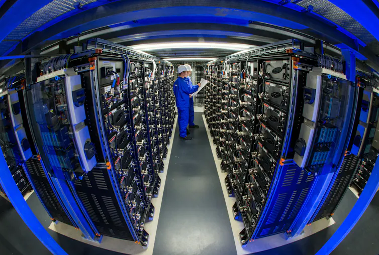 Two engineers inspect shelves of equipment.