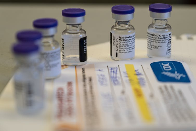 Glass bottles of the Pfizer COVID-19 vaccine next to medical form