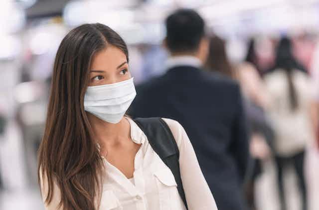 A woman at an airport, wearing a mask