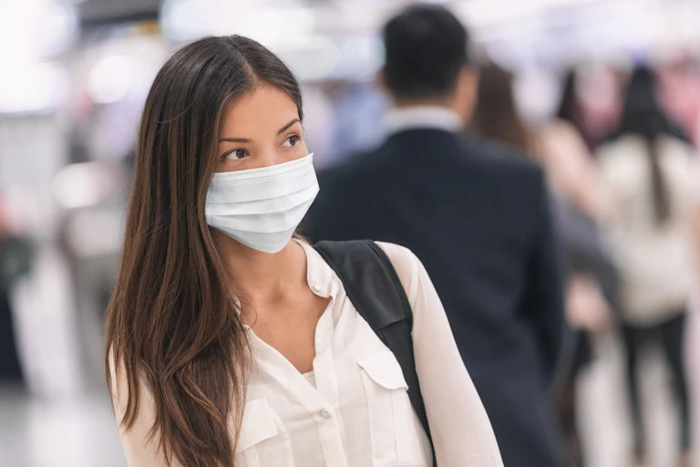 A woman at an airport, wearing a mask