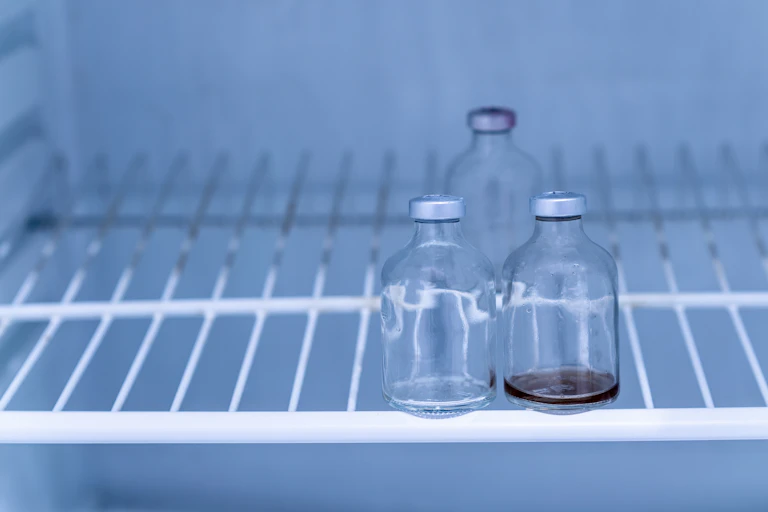 A photo of three empty vaccine vials in a freezer.