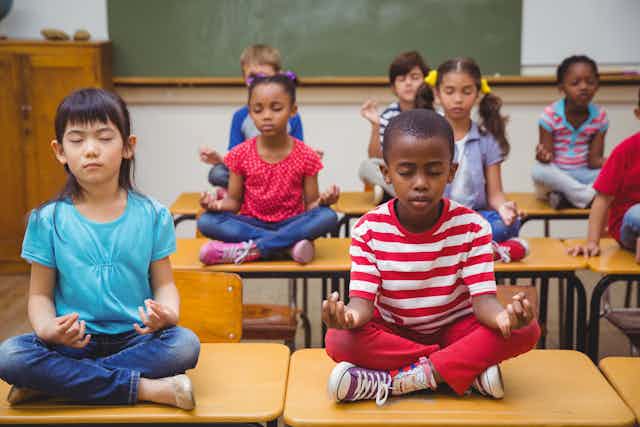 Schoolchildren meditating while in the lotus position.
