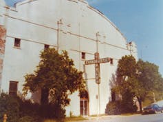 A cavernous white building with a cross attached as a marquee.