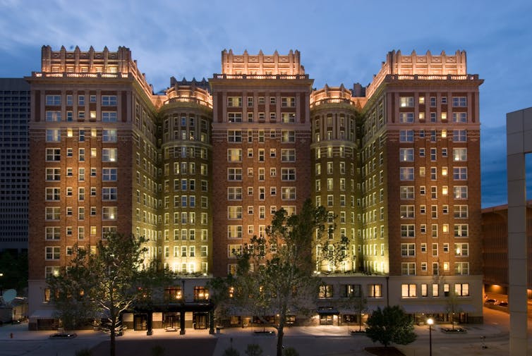 A massive brick building, lit up at dusk.