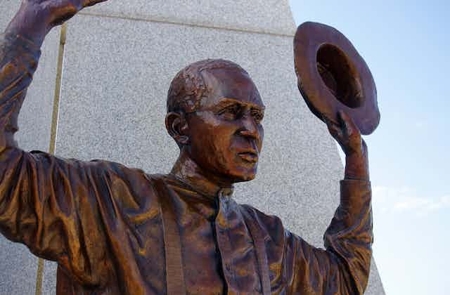 A bronze statue of a black man raising his hands.