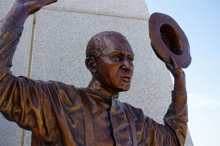 A bronze statue of a black man raising his hands.