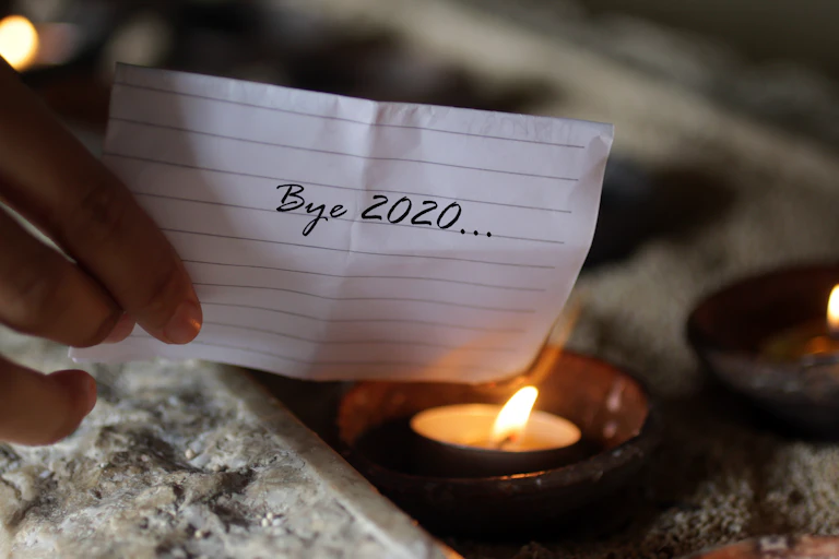 A piece of paper reading 'Bye 2020' held to a flame