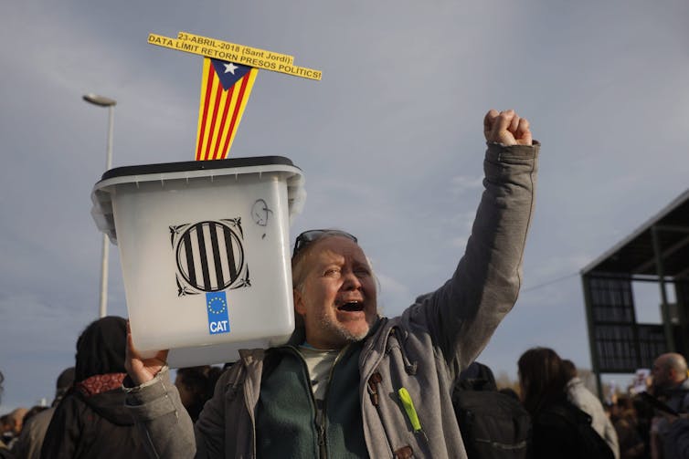 A man holds up a ballot box during a protest.