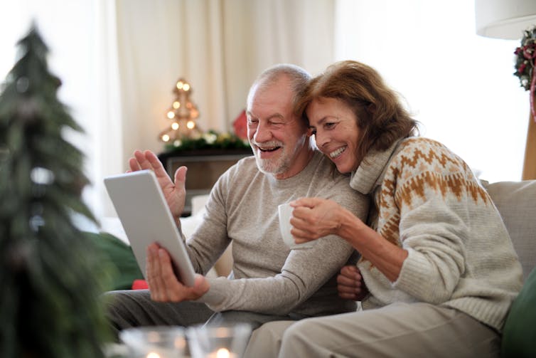 Senior couple smiling during a video call on a laptop with Christmas decorations in the background
