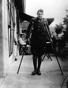 A man in army uniform stands on crutches.