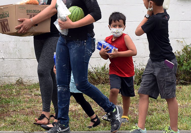 A family walks away carrying groceries in their hands