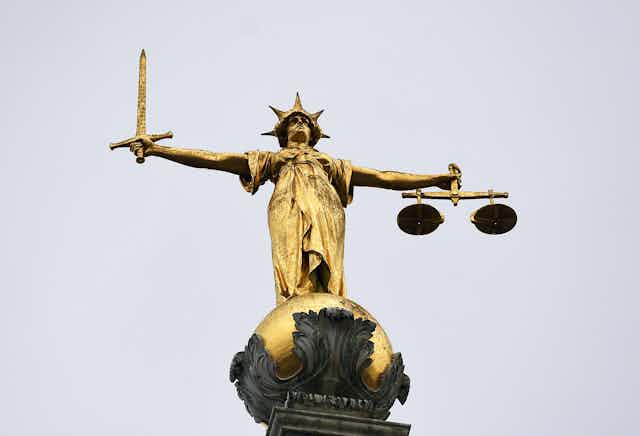 Golden statue of justice holding a sword in one hand and scales in the other