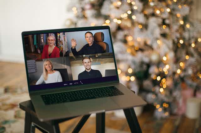 People celebrating Christmas over video conferencing, as shown on the screen of a laptop.