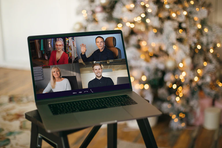 People celebrating Christmas over video conferencing, as shown on the screen of a laptop.