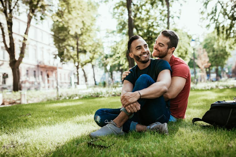 couple embrace while sitting on the grass