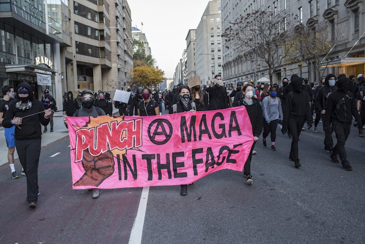 Manifestantes anti-Trump con un cartel que dice 'Golpea a MAGA (Make America Great Again) en la cara' en una marcha en Washington, DC.