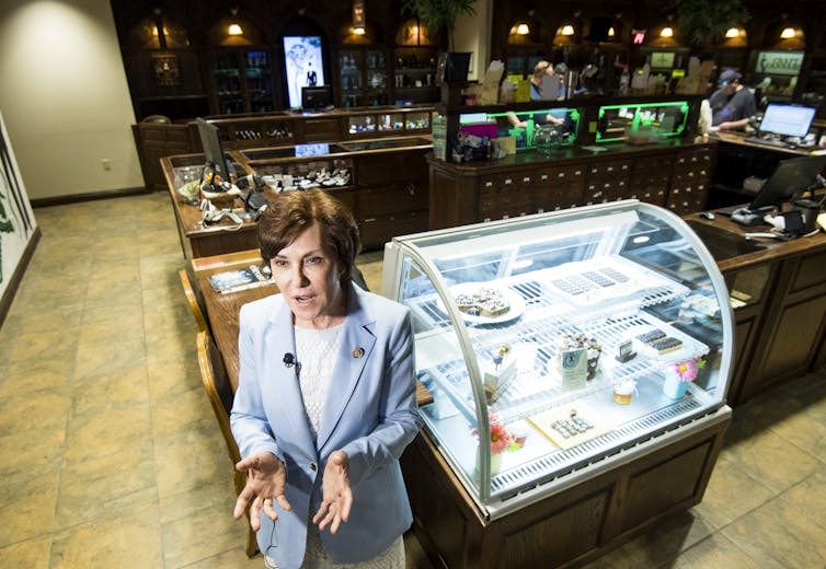 A woman in a blue suit stands in what looks like an upscale diner.