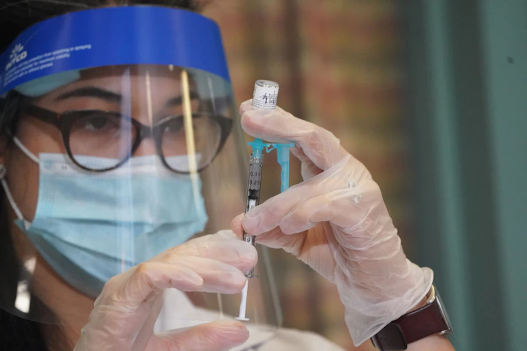 A pharmacist prepares a COVID-19 vaccine.