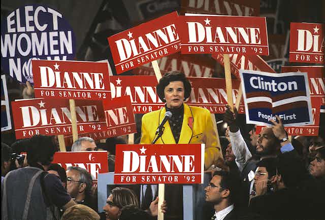 Feinstein speaks amid a crowd holding red 'Dianne' signs