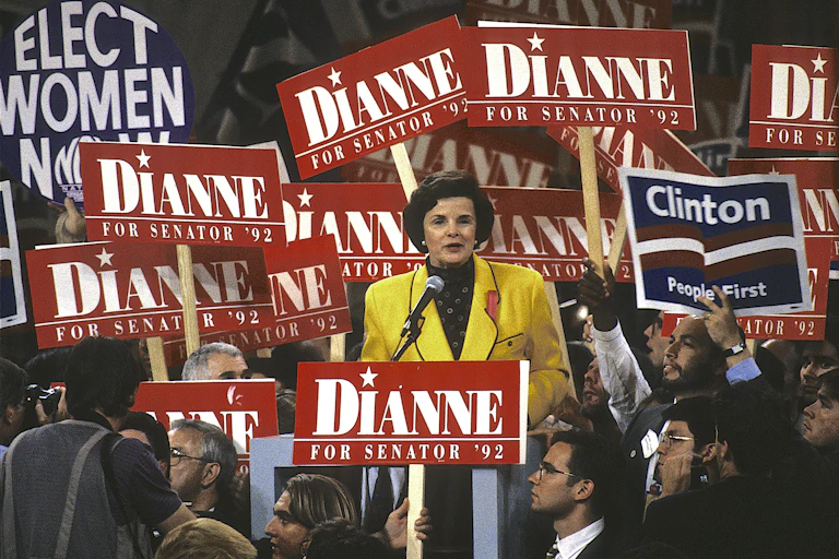 Feinstein speaks amid a crowd holding red 'Dianne' signs