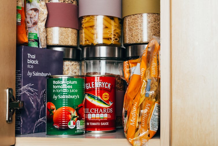 Cupboard containing tinned food and rice, dried pasta