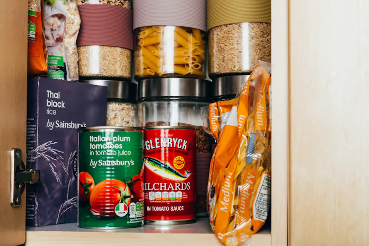 Cupboard containing tinned food and rice, dried pasta