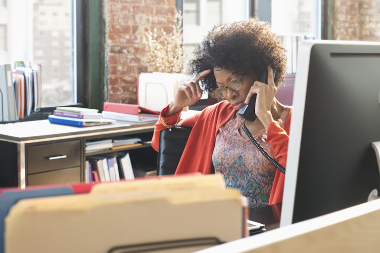 An African American female professor is frustrated speaking over the phone.