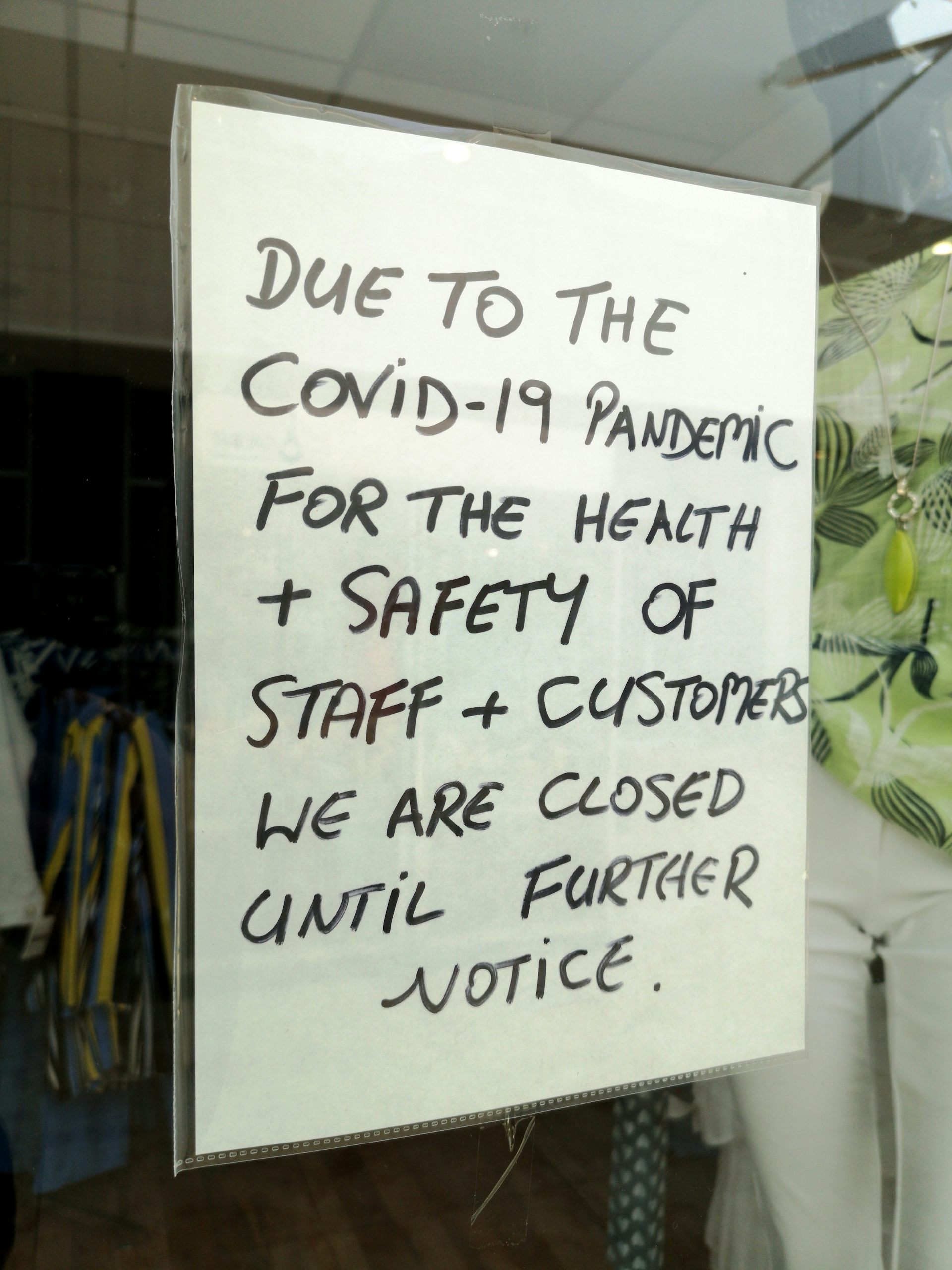 Kyltti kaupan ikkunassa, jossa lukee, että kauppa on suljettu toistaiseksi COVID-19:n vuoksi