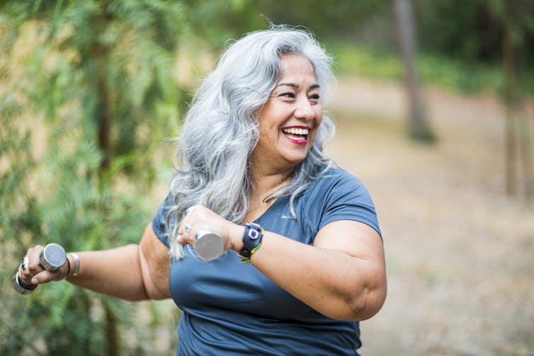 woman with grey hair working out with small weights