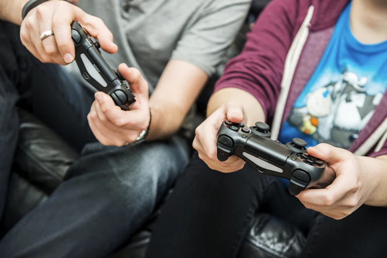 Man and young adult hold video game console controllers